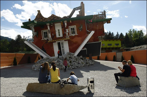 People sit in front of a house, which was built upside down by Polish architects Glowacki and Rozanski, in the western Austrian village of Terfens.