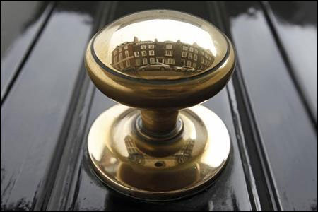 Houses are reflected in a door knob on a street in London.