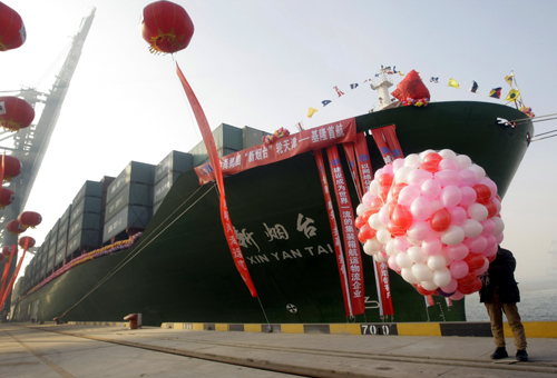 A man holding balloons stands next to a ship leaving to Keelung in Taiwan during a ceremony of the first direct sea transport across the strait, at Tianjin Port.