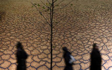 Office workers walk past a mural of a drought scene in this file photo.