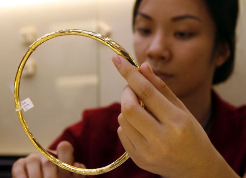 A woman displays gold for sale at a shop in Hanoi.