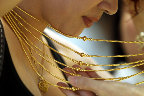 A customer tries on a gold necklace at a gold shop in Hanoi.