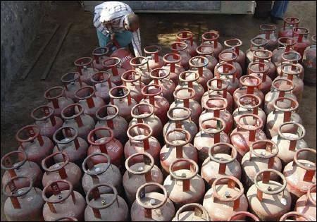 A vendor loads empty LPG cylinders onto a truck.