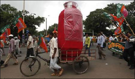 A man pulls a rickshaw loaded with a mock cooking gas cylinder.