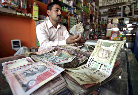 A shopkeeper counts Indian currency notes.