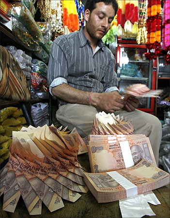 A Kashmiri shopkeeper makes a garland of Indian currency notes inside his shop in Srinagar.