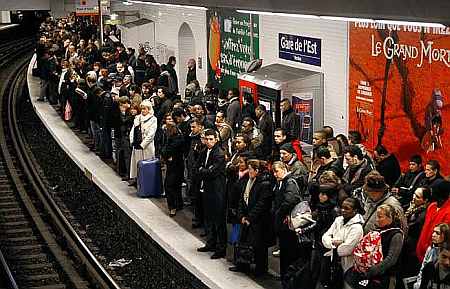 Commuters wait for a train at a metro station in Paris