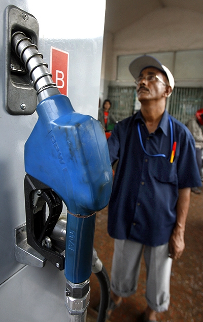 An attendant looks at the price board at a petrol station in Dhaka.