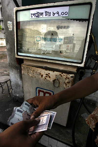 A station attendant receives money from a customer after filling up a car at a petrol station in Dhaka.