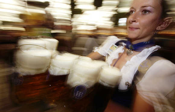 A waitress carries the traditional one-litre beer mugs at the opening of the Munich Oktoberfest.