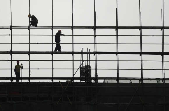 Labourers work on scaffolding at a residential construction site.