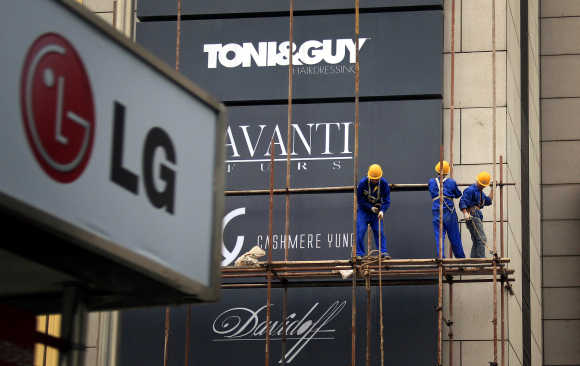 Workers erect scaffolding in front of advertising signs for foreign stores at a shopping mall in central Beijing.