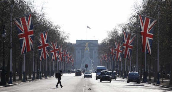 A man crosses the Mall, decked out in Union flags and with Buckingham Palace in the background, in London.