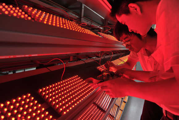 Employees measure the ageing levels of low energy consumption light bulbs at a factory in Nanjing, Jiangsu province, China.