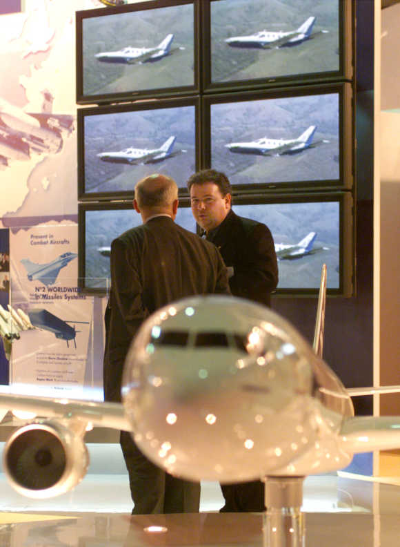 Sales representatives of French aerospace company Aerospatiale Matra chat behind a model of Airbus A340-500 Maken at the Asian Aerospace 2000 held in Singapore.