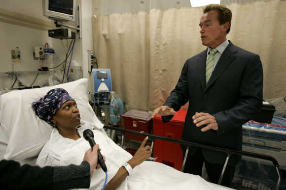 California's then-governor Arnold Schwarzenegger talks to a patient in the hospital.