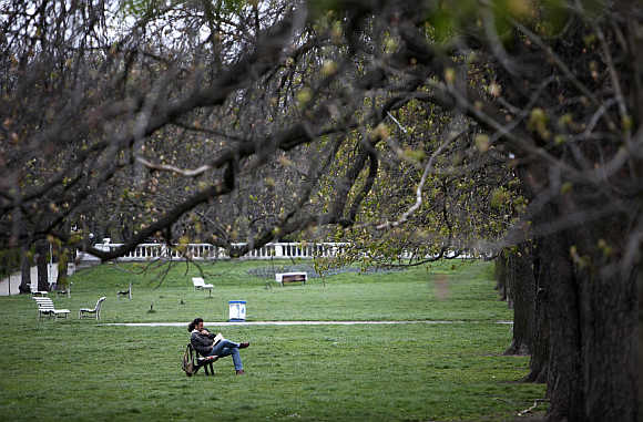 A man reads a book in a park in Sofia.