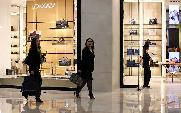 Women walk past a shop selling luxury shoes and bags at a mall in Jakarta.