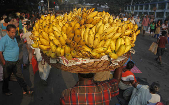 A vendor carries a basket of bananas to sell at a market in Kolkata.