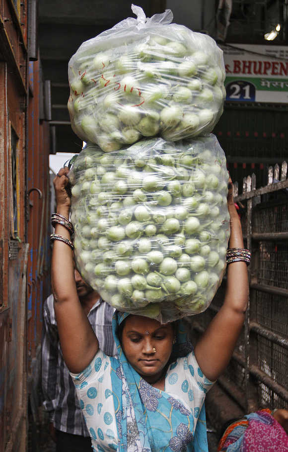 A woman carries bags of white brinjal at a wholesale vegetable market in Ahmedabad.