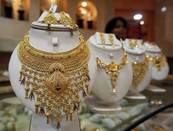 Saleswoman stands behind the showcased gold necklaces at a jewellery showroom in Agartala.