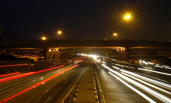 Traffic moves under a flyover along a busy road in New Delhi.