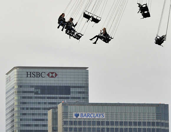 Financial offices of Canary Wharf are seen behind visitors to the O2 arena enjoying a fairground ride in east London.