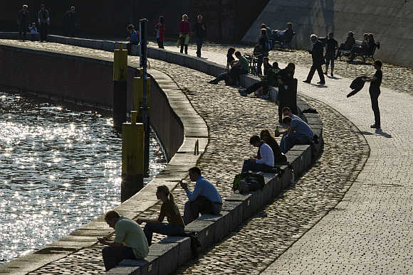 People relax on river Spree embankment on sunny spring day in Berlin.