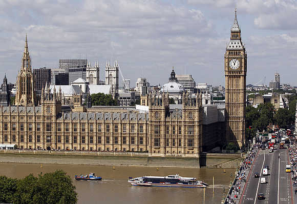 Traffic on the road and the Thames passes the Houses of Parliament in London.