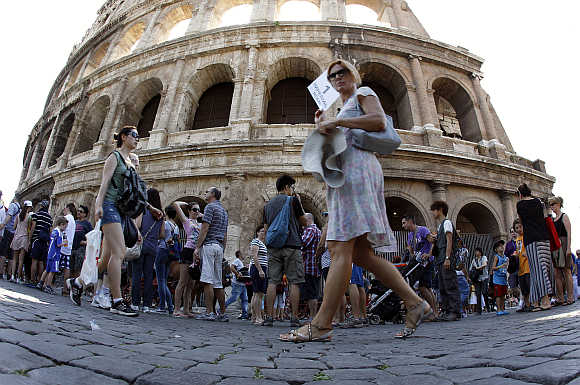 Tourists walk in front of Rome's ancient Colosseum.