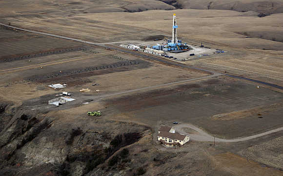 An oil drilling rig operates near homes and farm fields outside Williston, North Dakota.