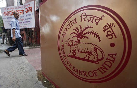 A man walks past an RBI logo in front of its building in Kolkata.