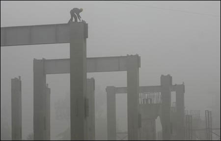 A Delhi Metro Rail Corporation worker works amidst the thick fog at a construction site in New Delhi.