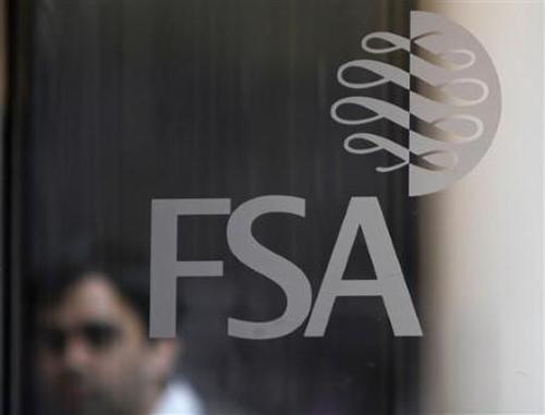 A man is seen behind the entrance door of the offices of the Financial Services Authority in Canary Wharf, London