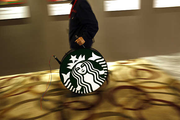 A man carries a Starbucks logo sign after a corporate event at a hotel in Shanghai.
