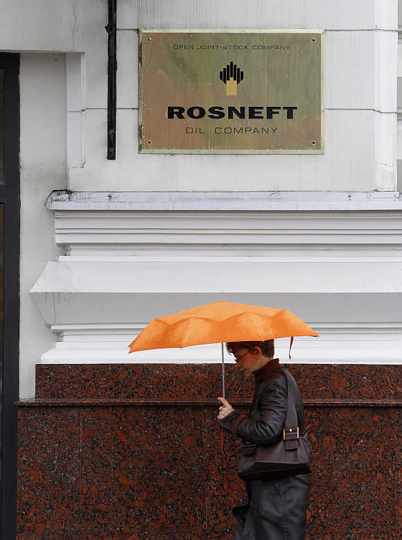 A woman walks past under a logo of Russian state oil firm Rosneft at its office in Moscow.
