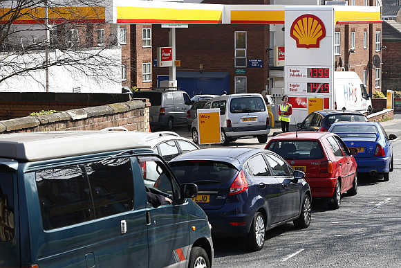 A worker monitors the queue as motorists wait for fuel at a filling station in Liverpool, northern England.
