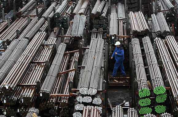 A workers walks through finished steel bars of different quality and size at a mill. 