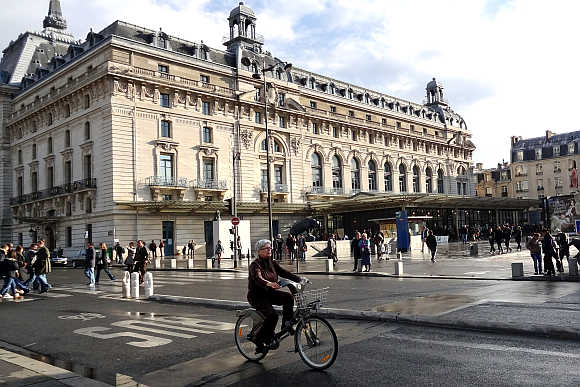 A cyclist rides past the Orsay Museum in Paris.