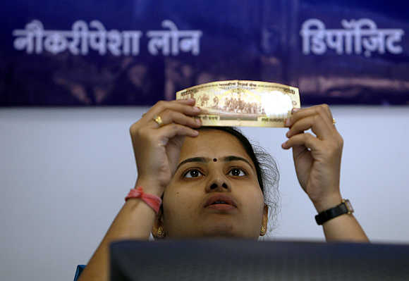 An employee checks a Rs 500 note at a bank's microfinance division in Mumbai.