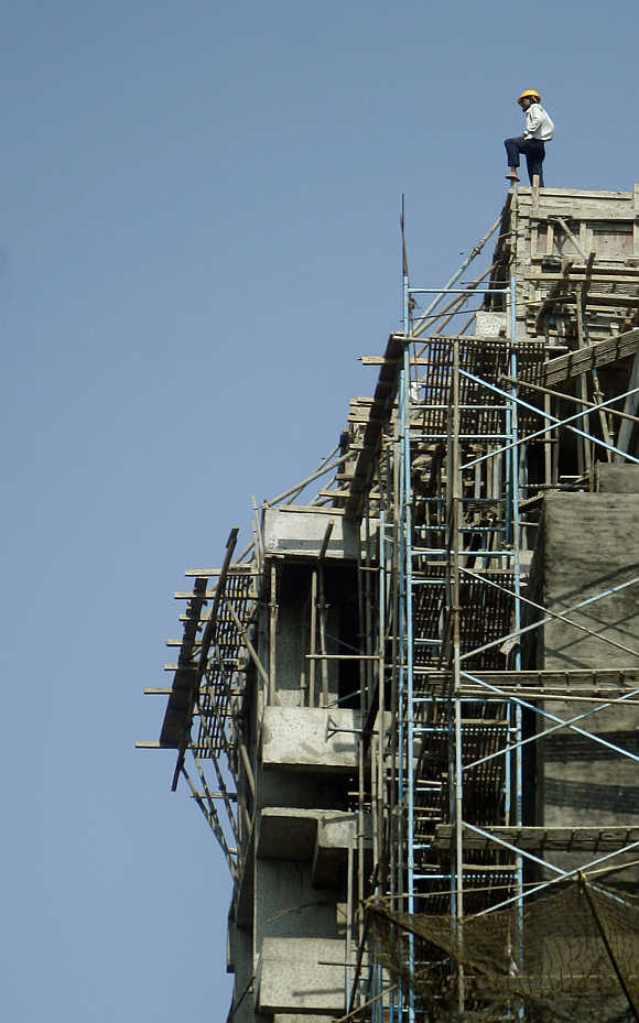A worker stands on top of a building under construction in Mumbai.