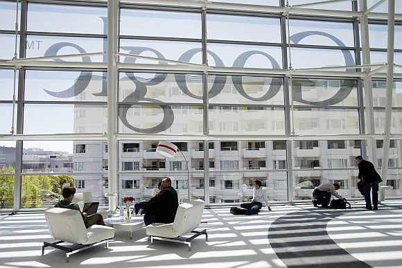 Attendees sits in front of a Google logo during Google I/O Conference at Moscone Center in San Francisco.
