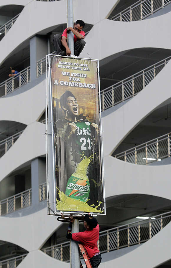 Workers install an energy drink advertising billboard outside a shopping mall in Manila.