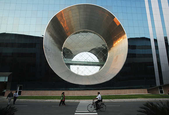 Employees walk and cycle in front of a building dubbed the 'washing machine', a well-known landmark built by Infosys at the Electronics city IT district in Bangalore.