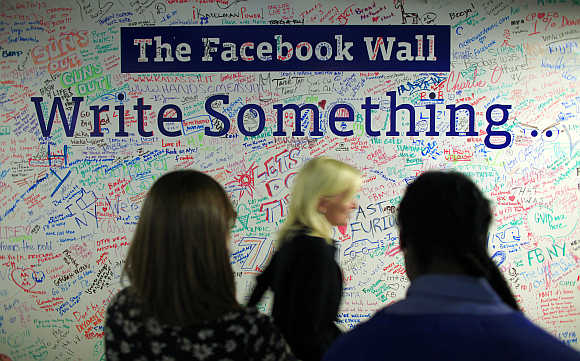 People walk past the Facebook wall inside their office in New York.