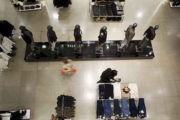 A customer walks past an employee arranging shoes at a store in Madrid.