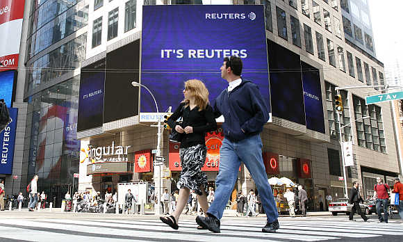 Pedestrians walk past the Reuters building in Times Square in New York.