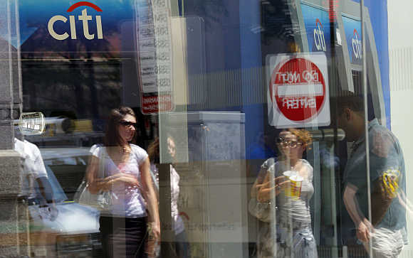 Pedestrians are reflected in the window of a Citibank branch in Boston.