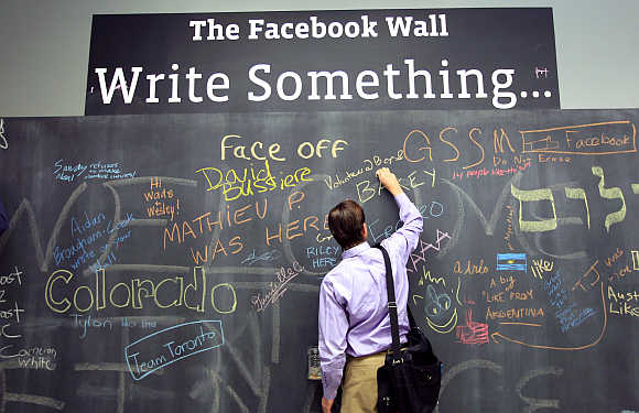 An employee writes a note on the message board at the new headquarters of Facebook in Menlo Park.