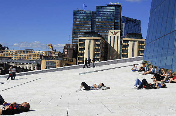 People sunbathe in front of the Oslo Opera House, the home of the Norwegian National Opera and Ballet, in Oslo